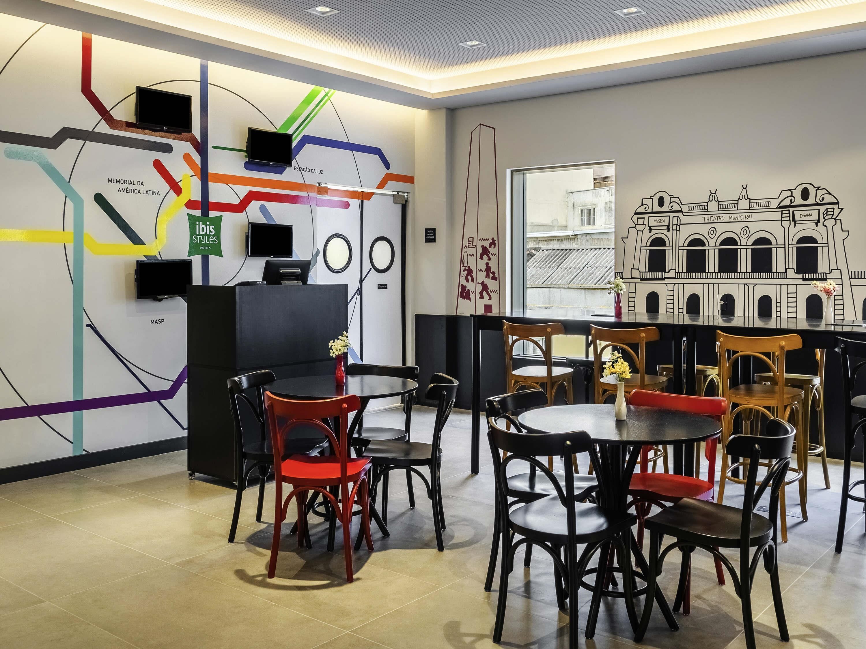 A modern interior with a reception desk, seating area, and a mural of a theater.