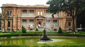 A historic building with a central courtyard, a fountain, and well-manicured gardens.