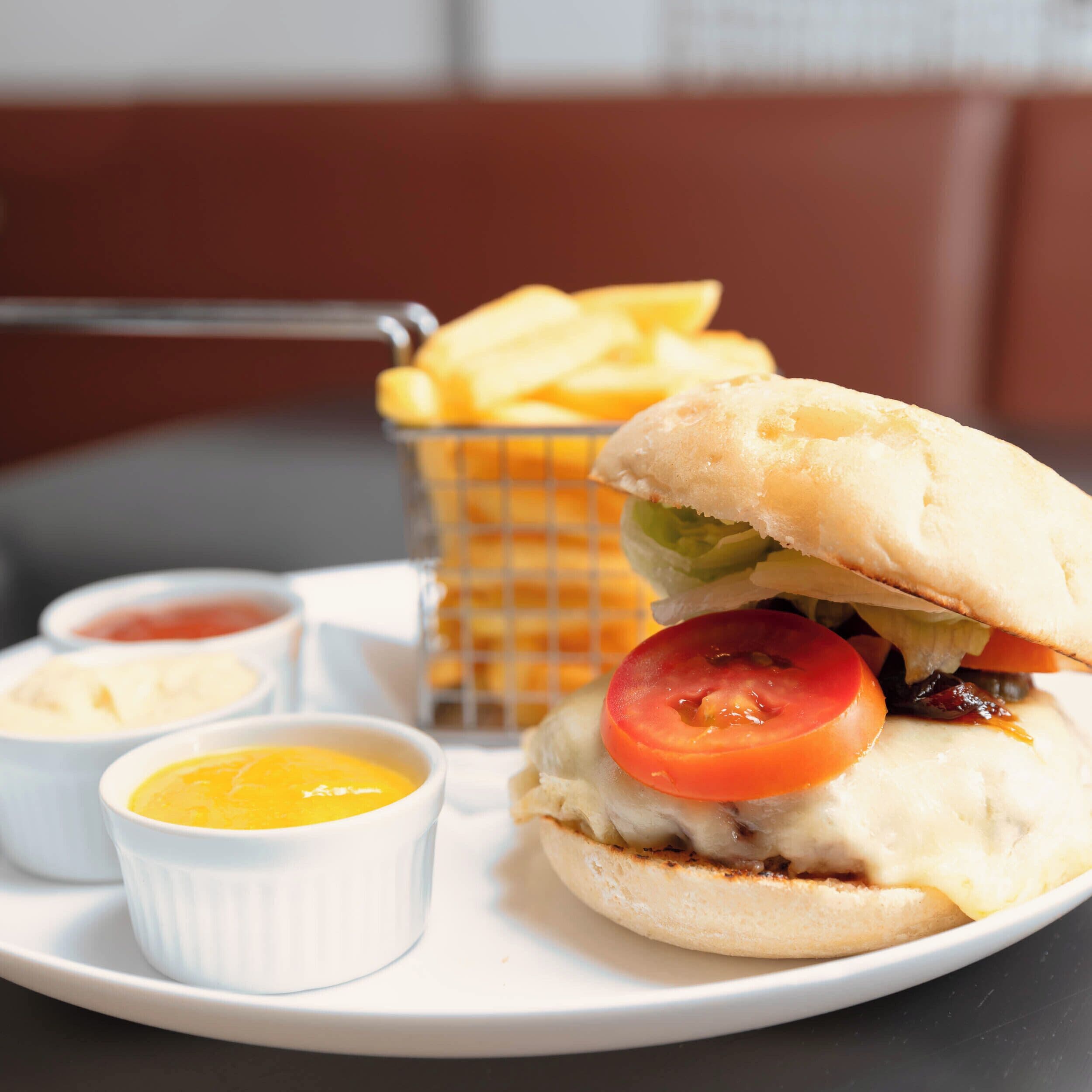 A sandwich with a side of fries and small containers of condiments on a plate.