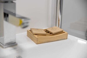 A wooden soap dish with two bars of soap on a white countertop.