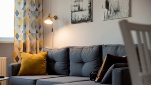 Ein modulares Sofa mit vielen Kissen, eine Stehlampe und abstrakte Wandbilder.