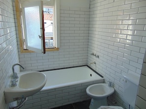 A bathroom with white tiled walls, a bathtub, a sink, and a toilet. - Hostel Playa Grande (Mar del Plata)