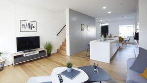 Una sala de estar moderna con una televisión de pantalla plana, una mesa de centro y un sofá.