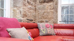 Ein rotes Ledersofa mit einem Kissen mit der Aufschrift 'LOVE' und einem weiteren mit einem Blumenmuster.