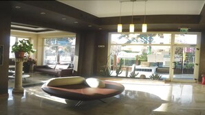 Un hall d’entrée moderne doté d’un grand espace salon, d’une plante en pot et d’une vue sur l’extérieur.