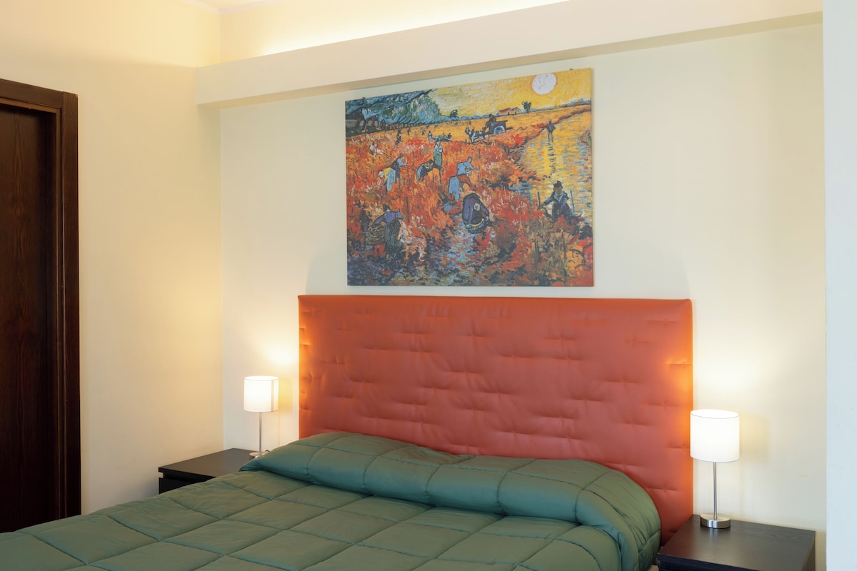 Une chambre à coucher avec un lit, deux tables de chevet, une commode et un tableau accroché au mur.