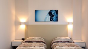Une chambre avec deux lits, une œuvre d’art accrochée au mur et des lampes de chevet.