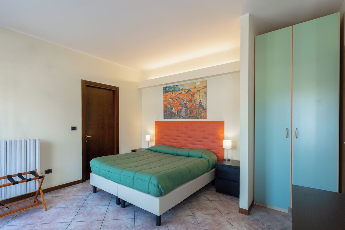 A bedroom with a bed, a wardrobe, a radiator, and a painting on the wall.