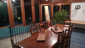 A wooden dining table with chairs, a potted plant, and a pendant light. - Azzurro Hotel Residence (L'Aquila)