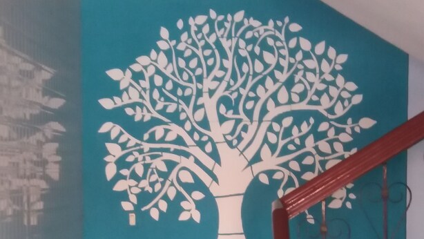 Un escalier avec un mur bleu orné d’une fresque représentant un arbre blanc et d’illustrations de bambous.