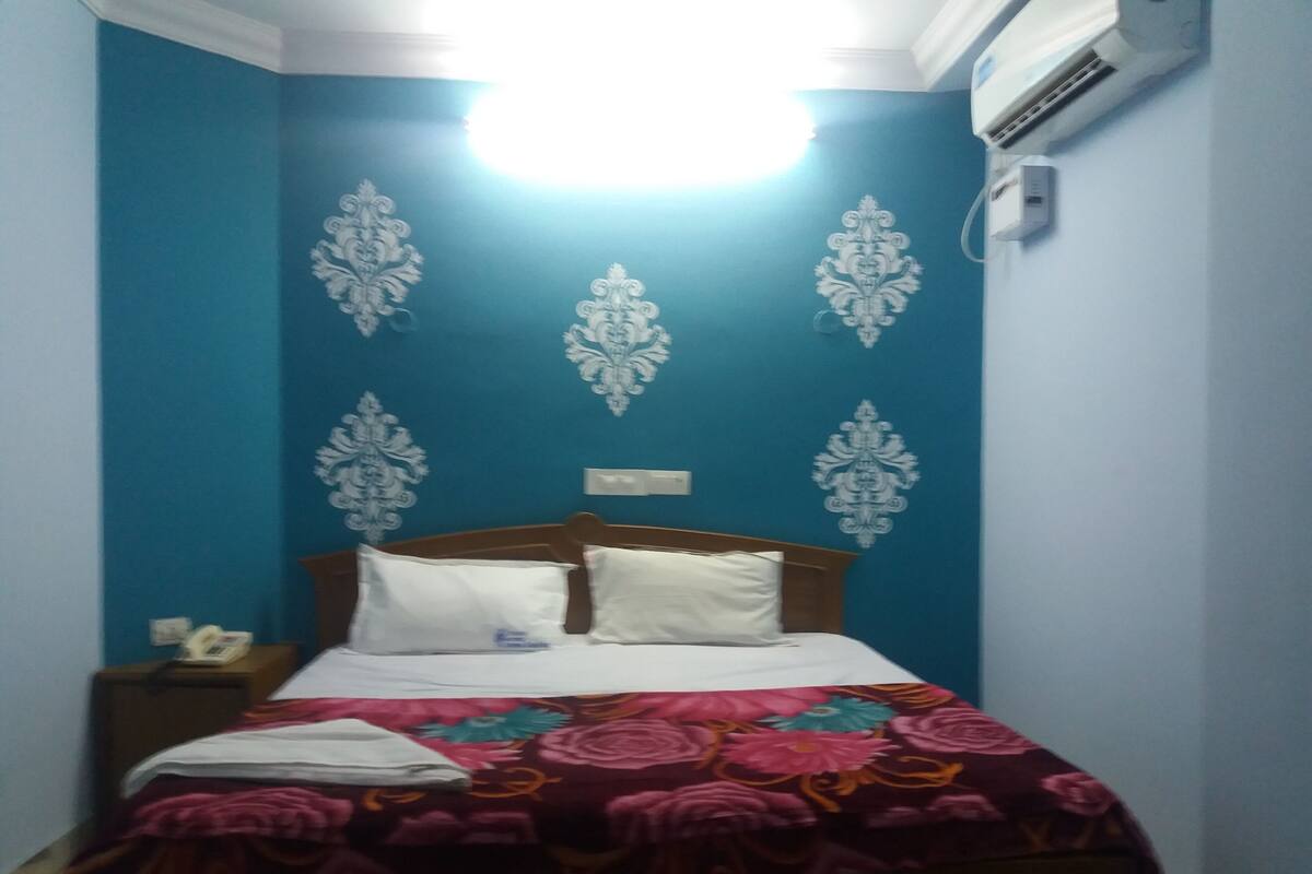 Un dormitorio con una cama, una mesita de noche y un aire acondicionado instalado en la pared.