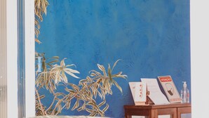A room with a blue wall, a wooden cabinet with papers, and a plant. - Pousada Costamar (Porto Seguro)