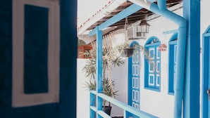 A view through a blue-framed window of a building with white walls and blue doors. - Pousada Costamar (Porto Seguro)