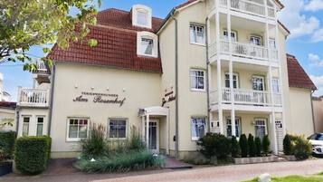 Monikerroksinen rakennus, jossa on parveke toisessa kerroksessa, kyltti, jossa lukee ”Hotel Rosenhof”, sekä päällystetty sisäänkäyntialue, jossa on viheralueita.