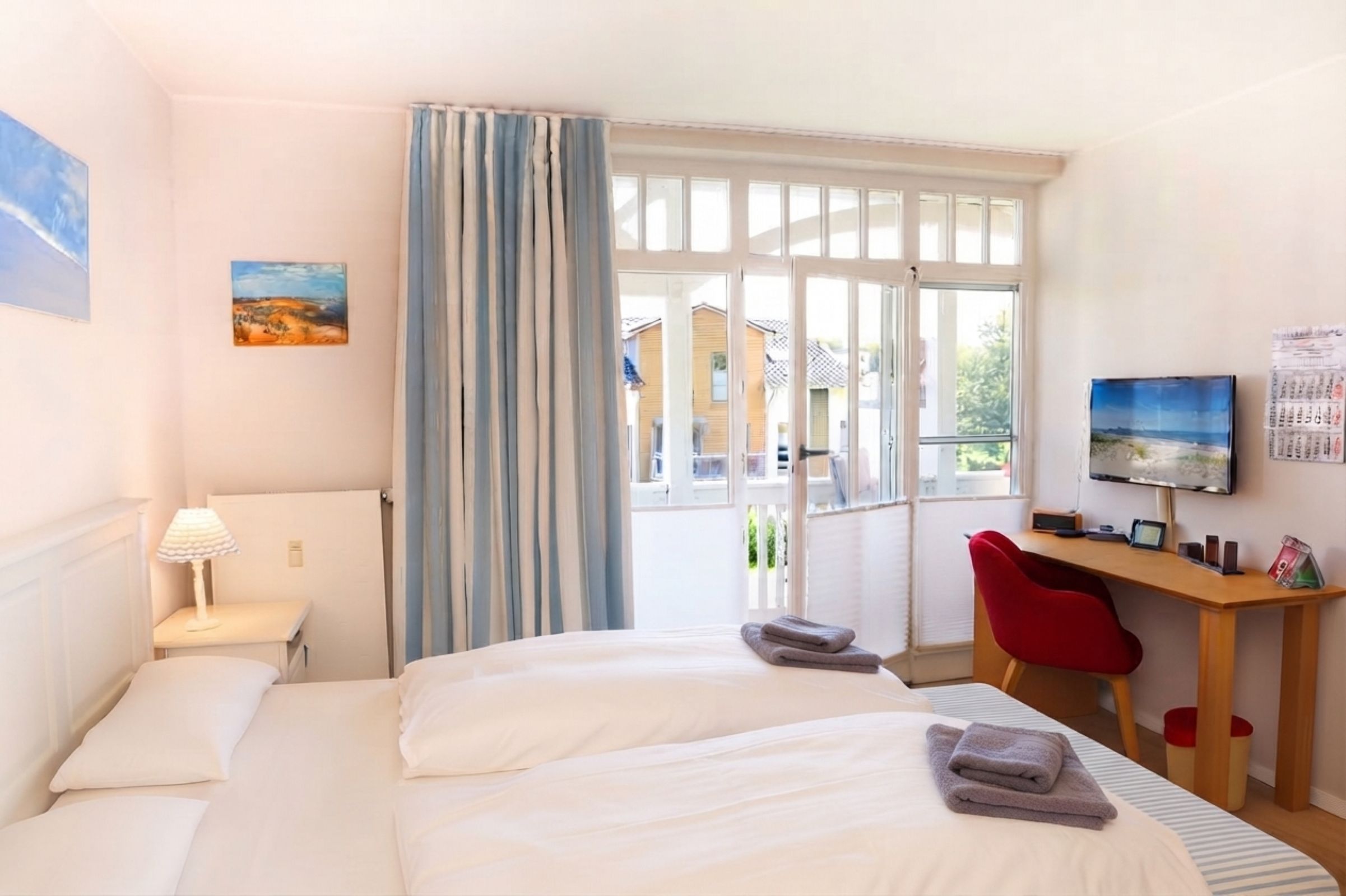 Ein Hotelzimmer mit einem Bett, einem Schreibtisch, einem Stuhl, einem Fernseher und einem Fenster mit Vorhängen.