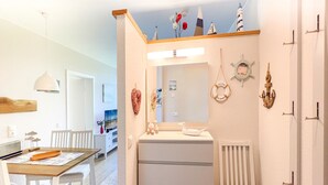 Un baño moderno con tocador blanco, espejo y decoración temática náutica.