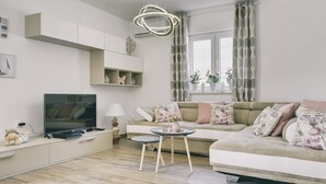Un salon moderne avec un canapé, un téléviseur et une petite table.