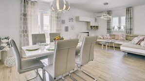 Un salon moderne avec un coin repas, comprenant un canapé, une table à manger et des chaises.