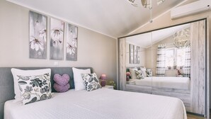 Une chambre avec un grand lit, un miroir et des œuvres d’art accrochées au mur.