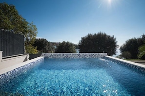 A clear blue swimming pool with a tiled edge, surrounded by trees and a wooden fence. - Great villa with private pool 50 meters from beach (Pjescana Uvala)