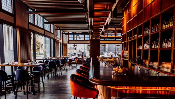 A modern bar with wooden shelves and a long counter. - Surety Hotel, Autograph Collection (Des Moines)
