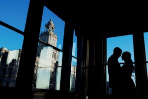 Pariskunnan hahmo piirtyy siluettina ikkunaa vasten, ja ikkunasta avautuu näkymä historialliseen rakennukseen.