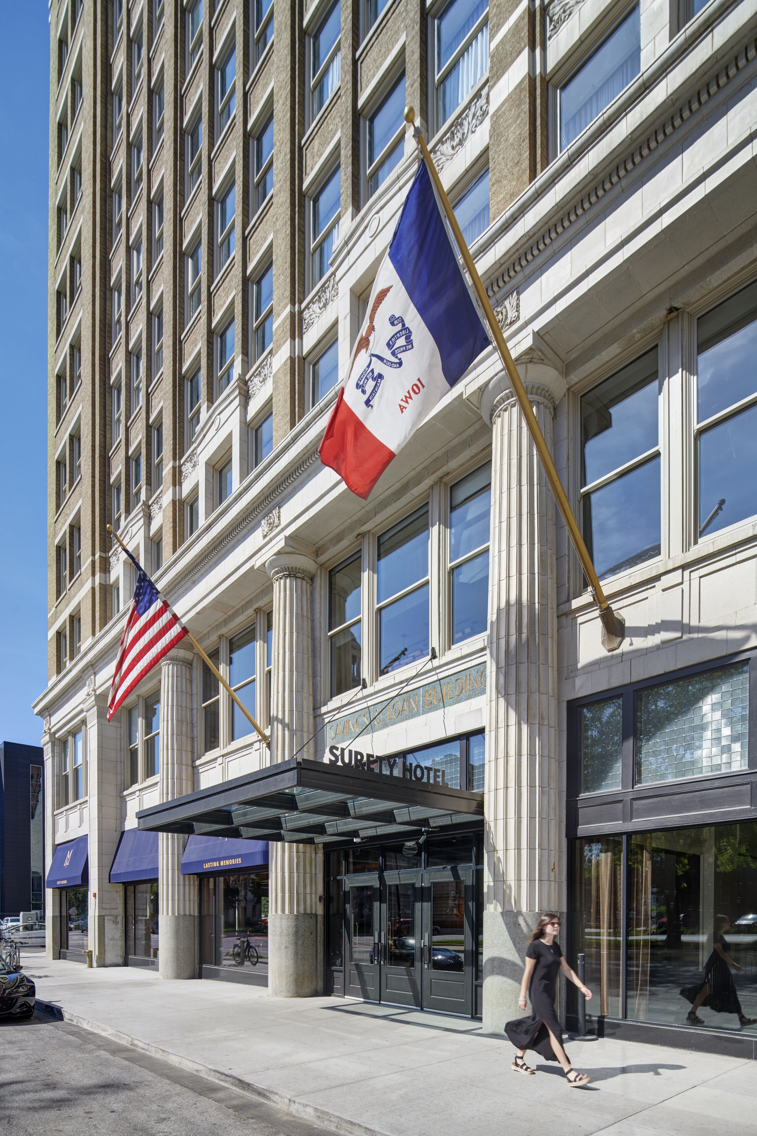 A hotel entrance with a classic facade, large windows, and a canopy over the entrance.