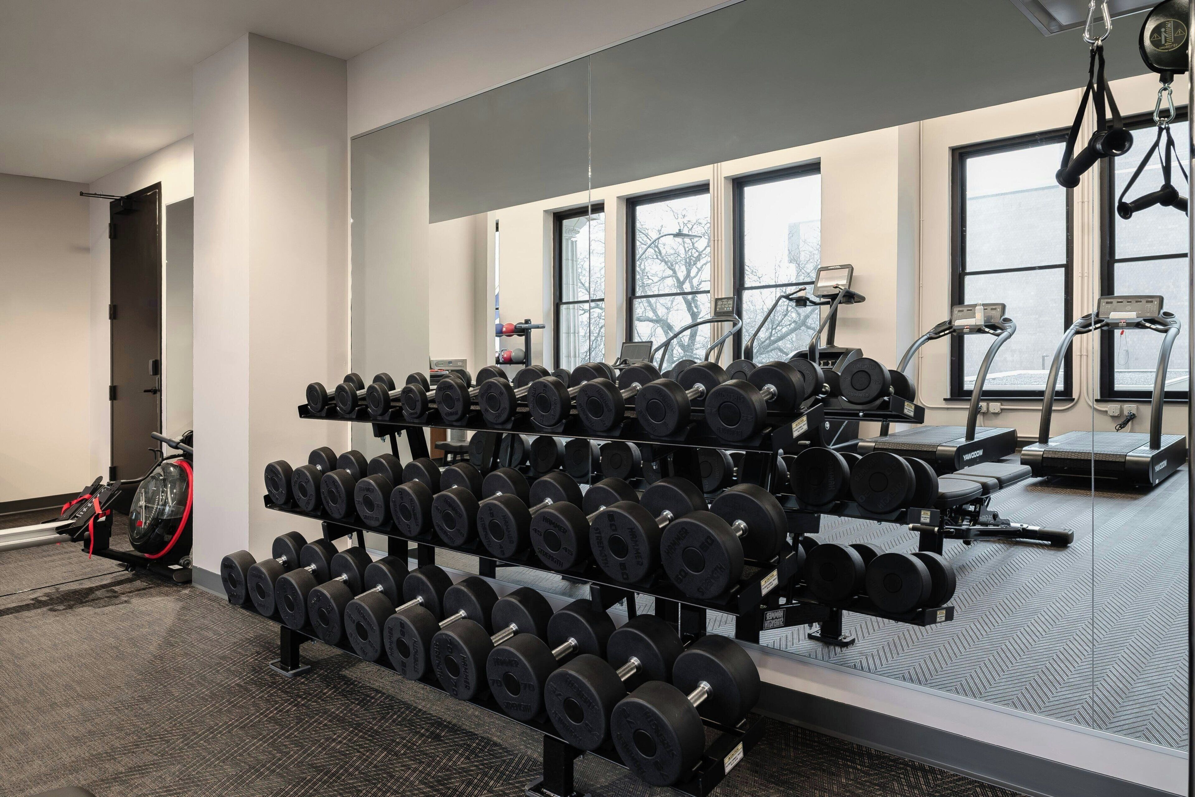 Un gimnasio con estantes para pesas, cintas de correr y equipamiento de ejercicio.