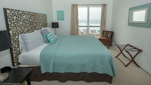 Une chambre avec un lit, une table de chevet, une lampe, une chaise et une vue sur la plage.