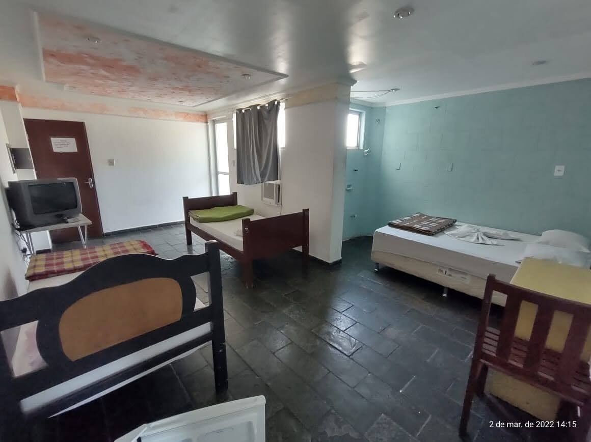 A room with a bed, a desk, a chair, a television, and a window.