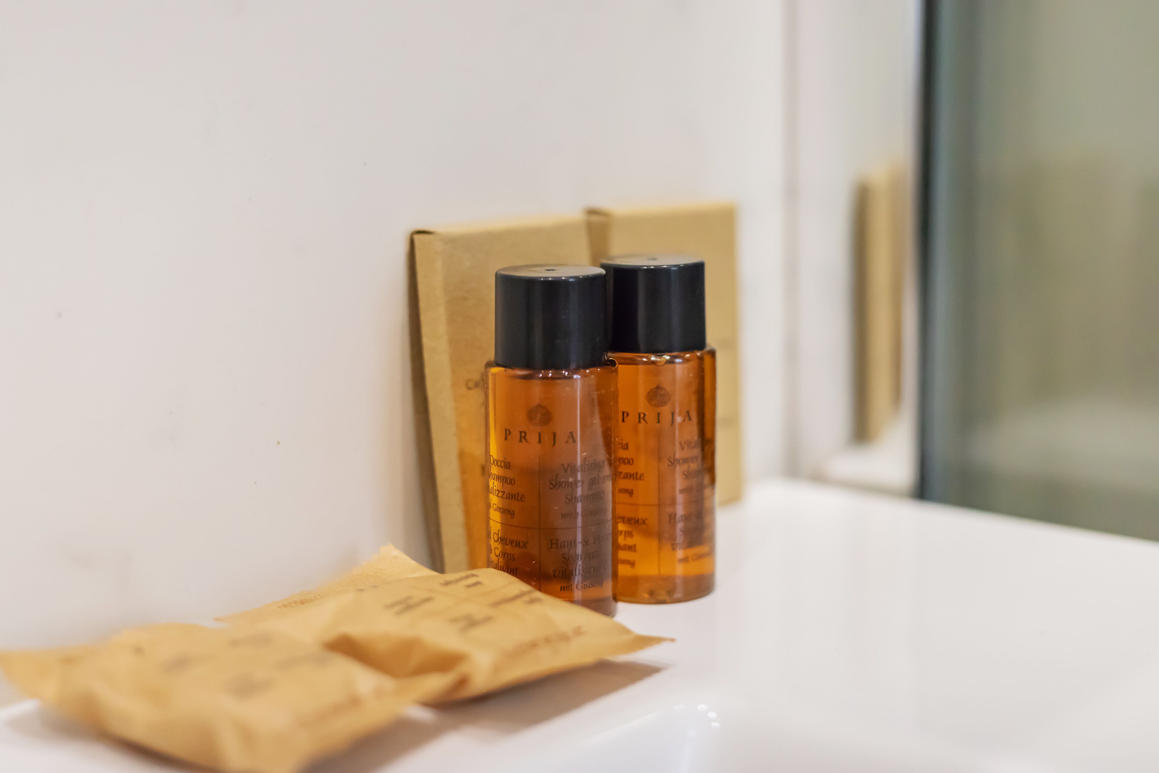 A bathroom with two bottles of shampoo and conditioner, a towel, and a cardboard box.