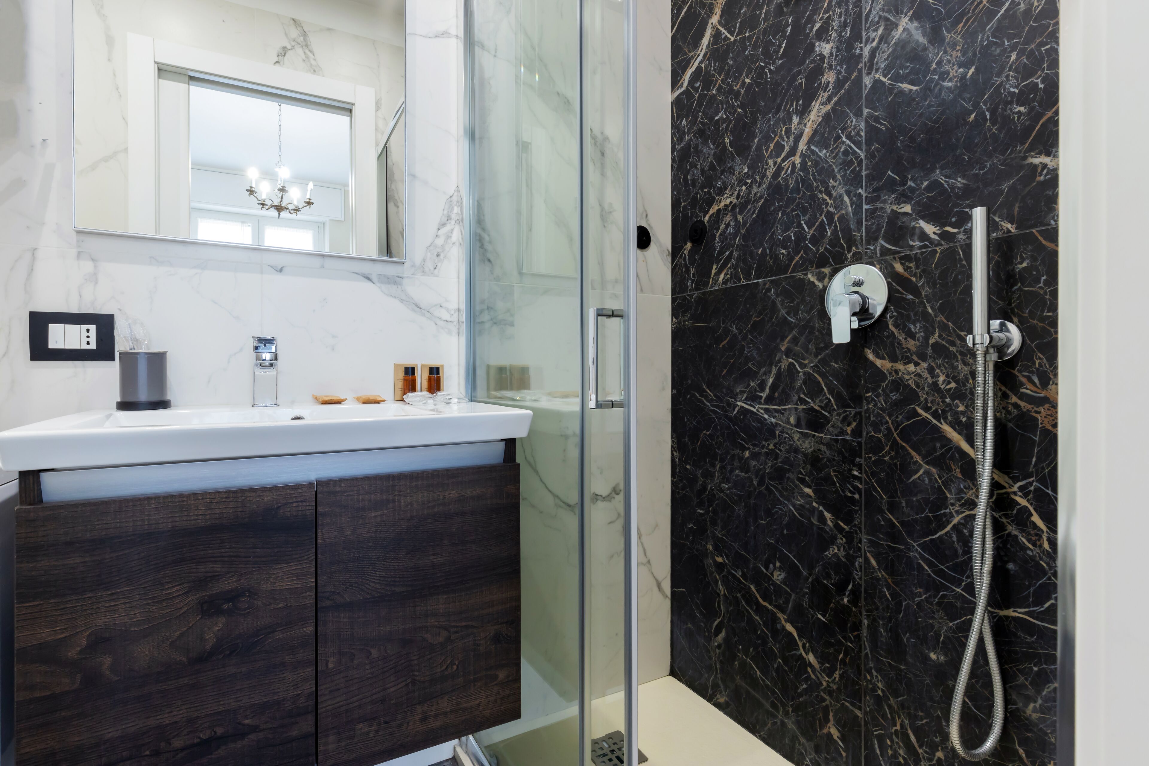 A modern bathroom with a glass shower enclosure, a marble vanity, and a black marble shower wall.