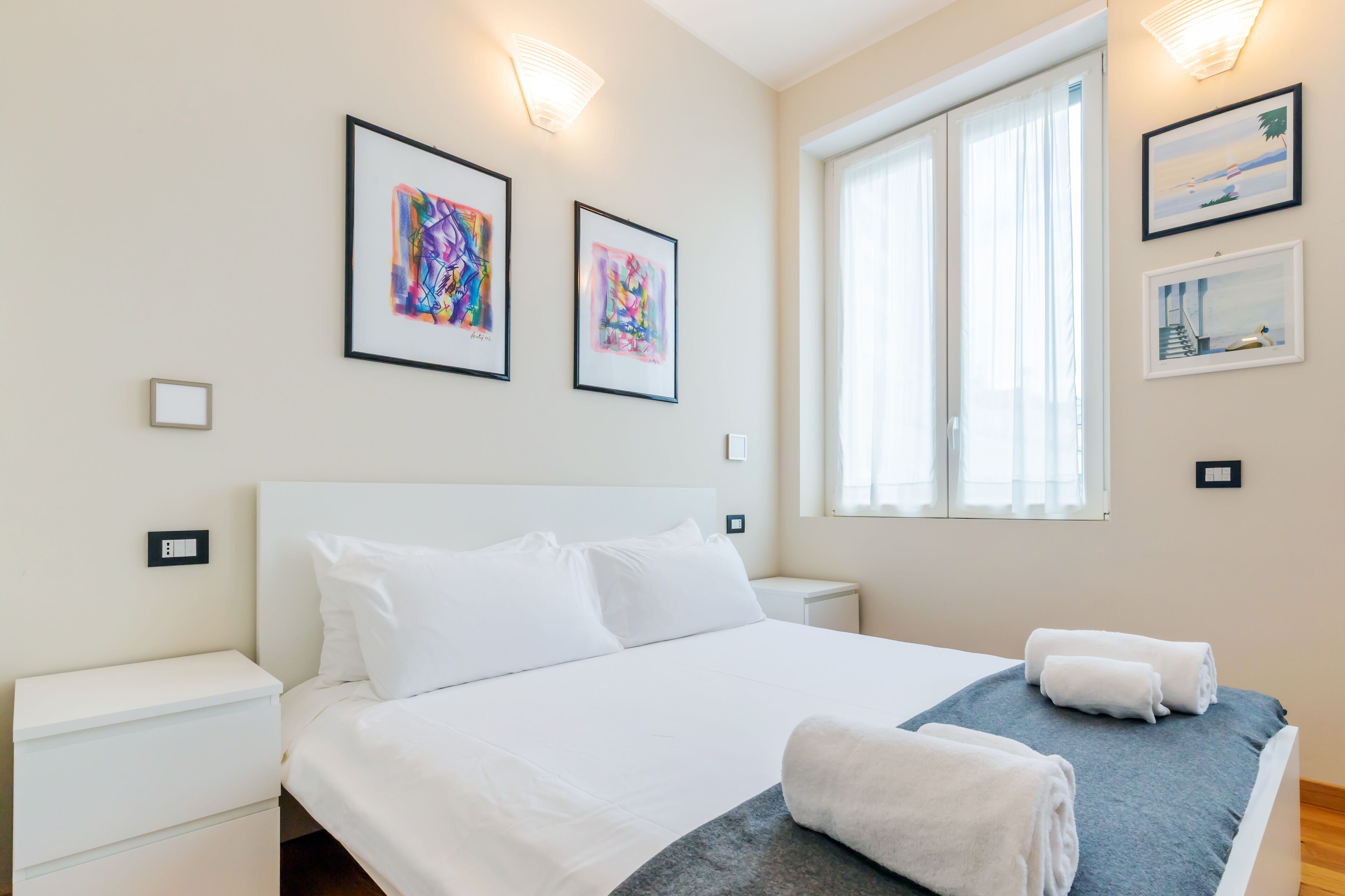 Ett välstädat hotellrum med en stor säng, vita sängkläder och ett fönster med gardiner.