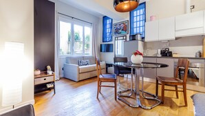 A modern kitchen with white cabinets, a dining table with chairs, and a large window. - Milan Retreats Cadorna (Milan)