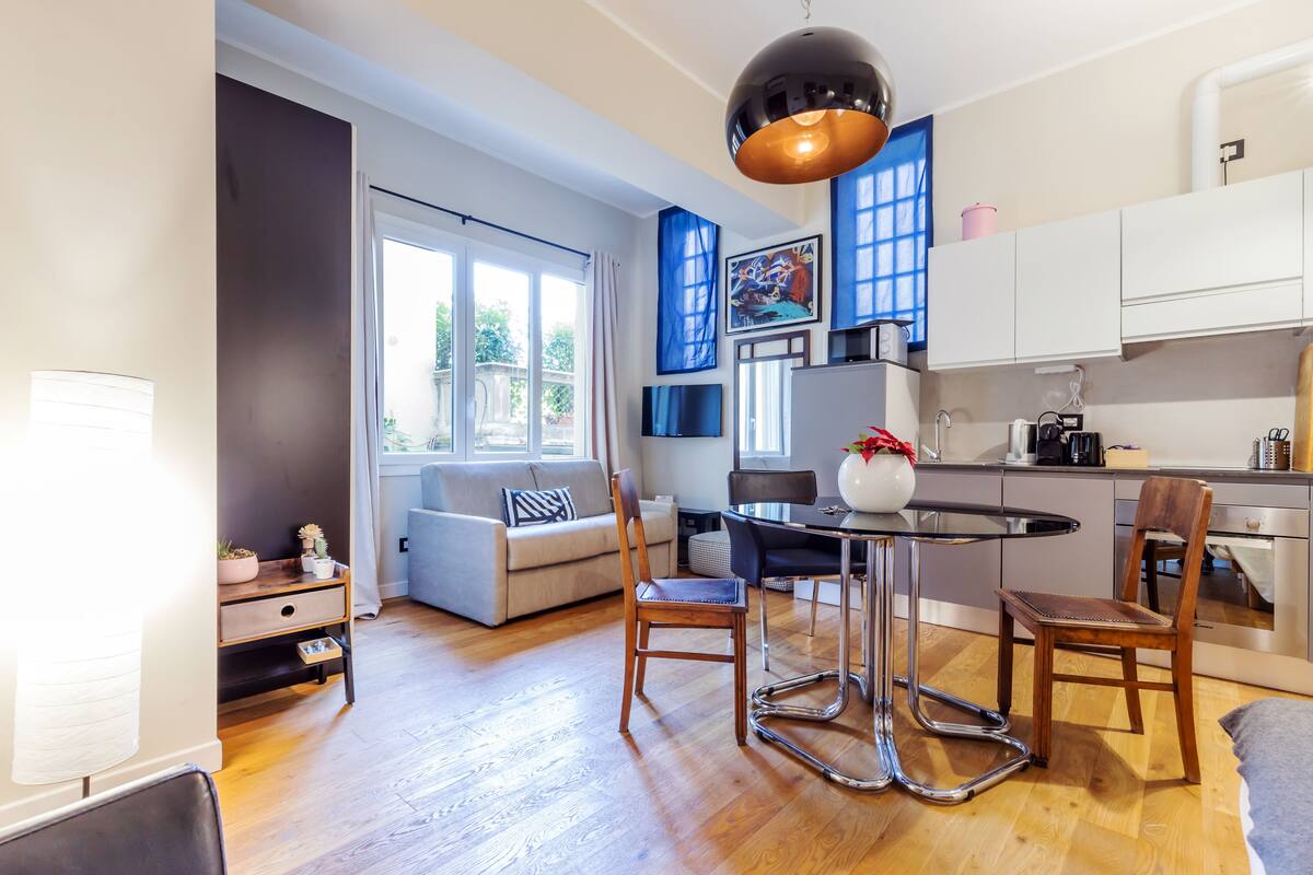 A modern kitchen with white cabinets, a dining table with chairs, and a large window.