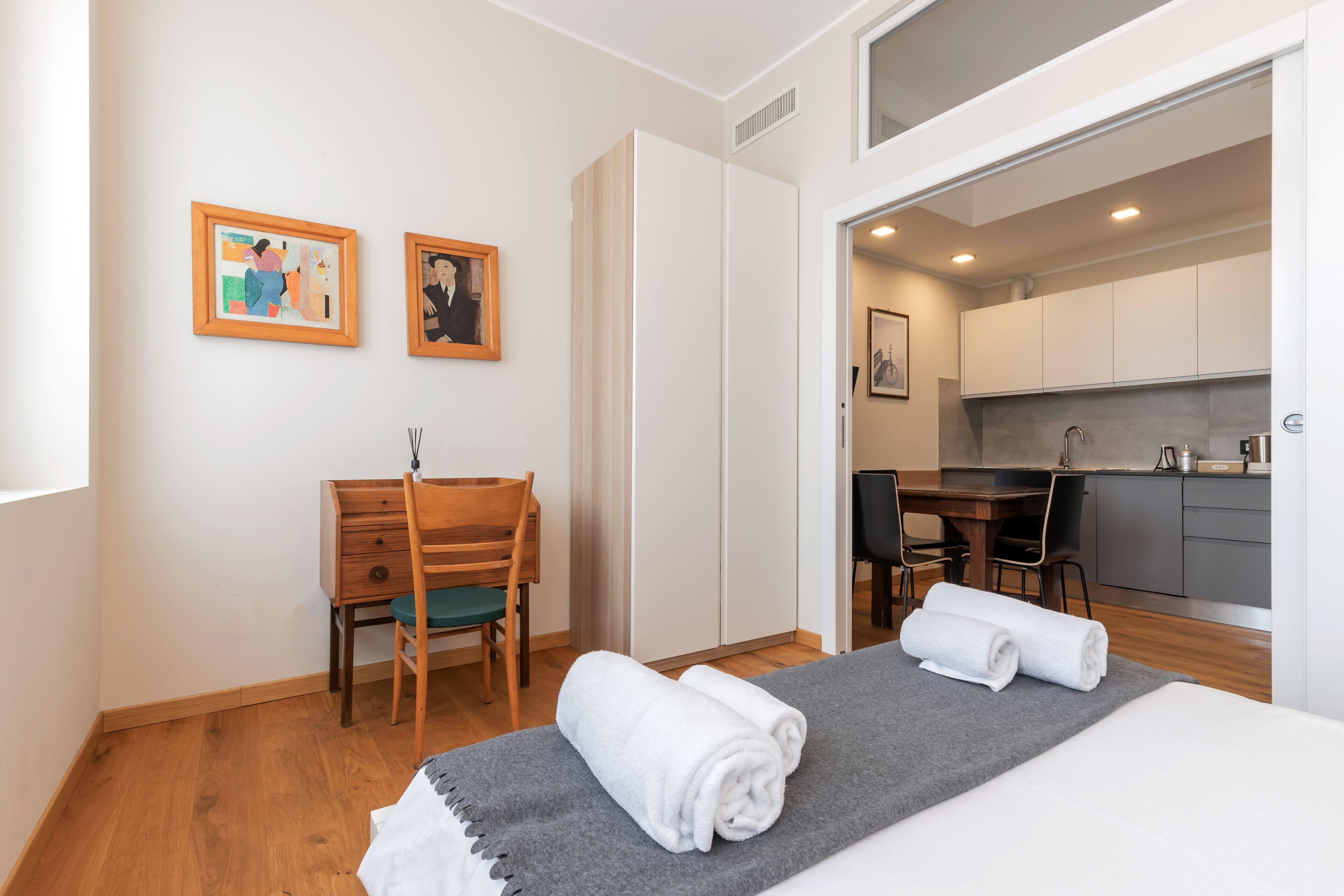 Ein Hotelzimmer mit Bett, Schreibtisch, Stuhl und einer Küchenzeile.