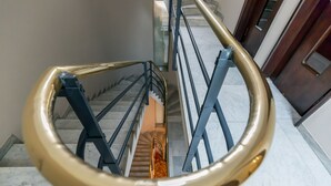 A spiral staircase with a golden handrail and blue railings. - Milan Retreats Cadorna (Milan)