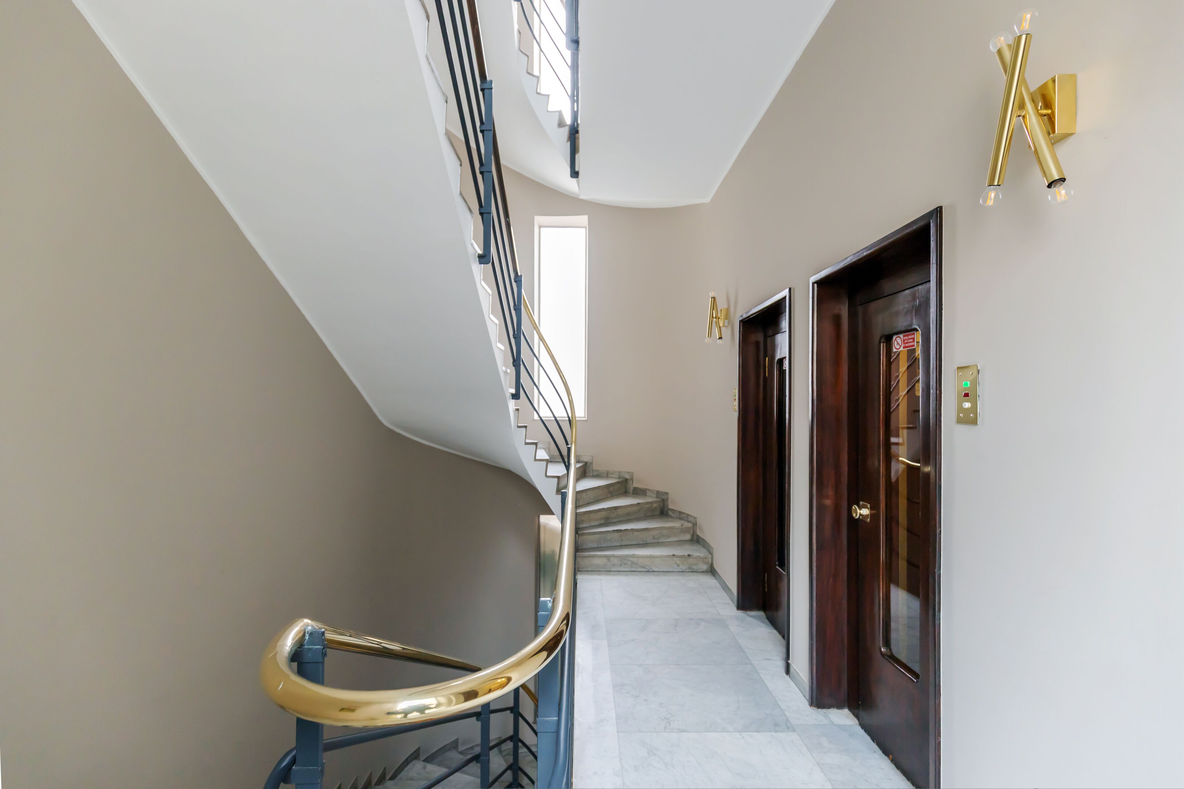 A curved staircase with a golden handrail leading to a landing.