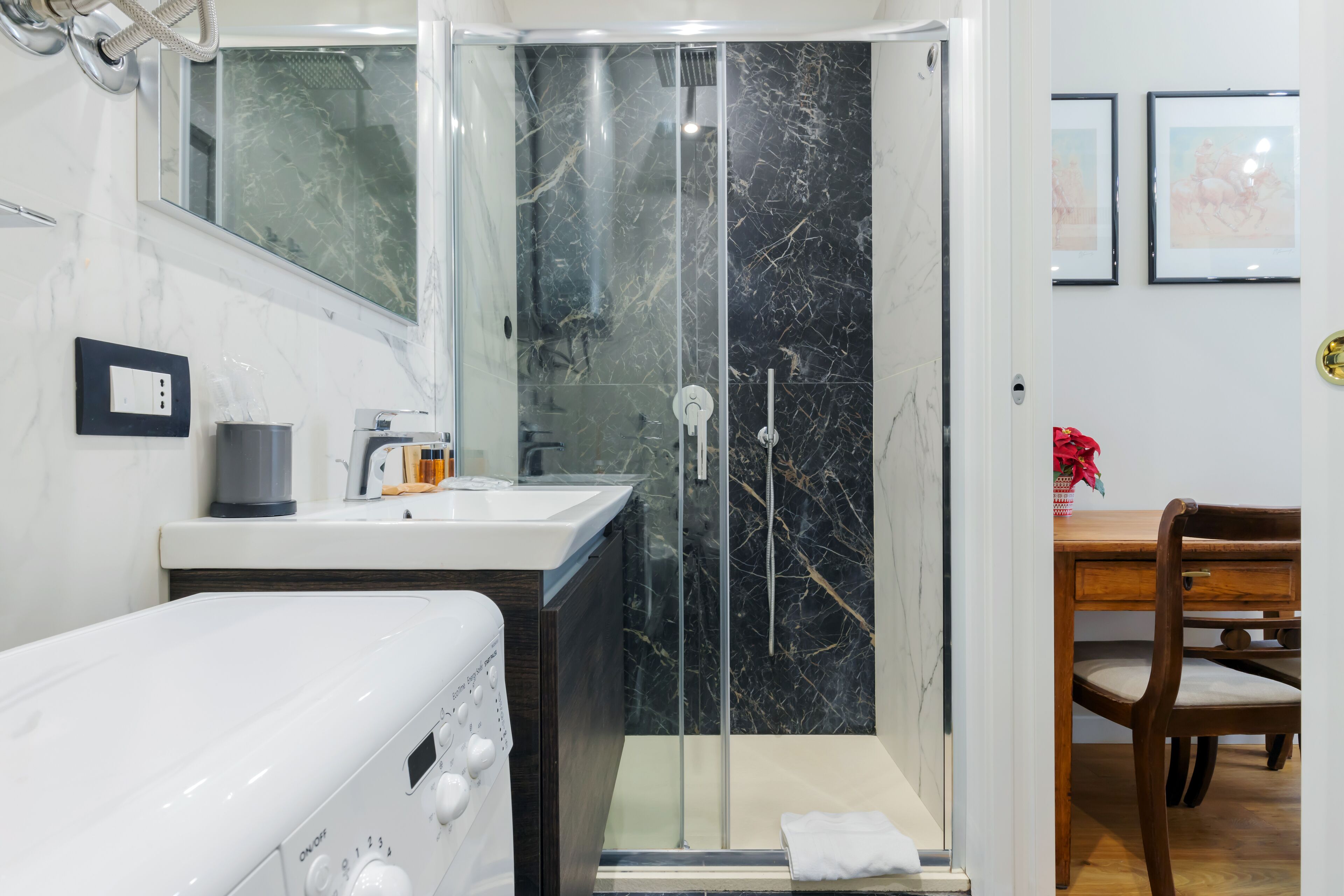 Une salle de bain avec une douche à parois de verre, un lavabo et une chaise en bois.