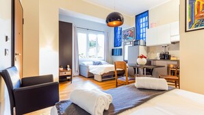 A modern hotel room with a bed, a desk, a chair, a small table, and a kitchenette. - Milan Retreats Cadorna (Milan)