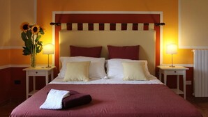 A double bed with a red and white headboard, two bedside tables with lamps, and a vase of sunflowers. - B&B La Lampara (Castellabate)