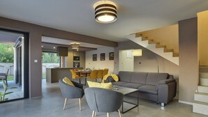 A modern living room with a sofa, coffee table, and chairs. There is a staircase and a dining area in the background. - Comfortable villa with private pool, just 1.5 km to the beach (Fazana)