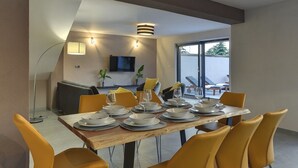 A dining area with a wooden table set for four, yellow chairs, and a TV mounted on the wall. - Comfortable villa with private pool, just 1.5 km to the beach (Fazana)