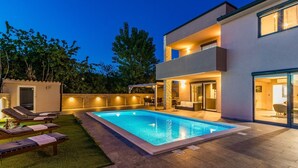 A modern two-story house with a swimming pool, outdoor seating, and a well-lit patio area. - Comfortable villa with private pool, just 1.5 km to the beach (Fazana)