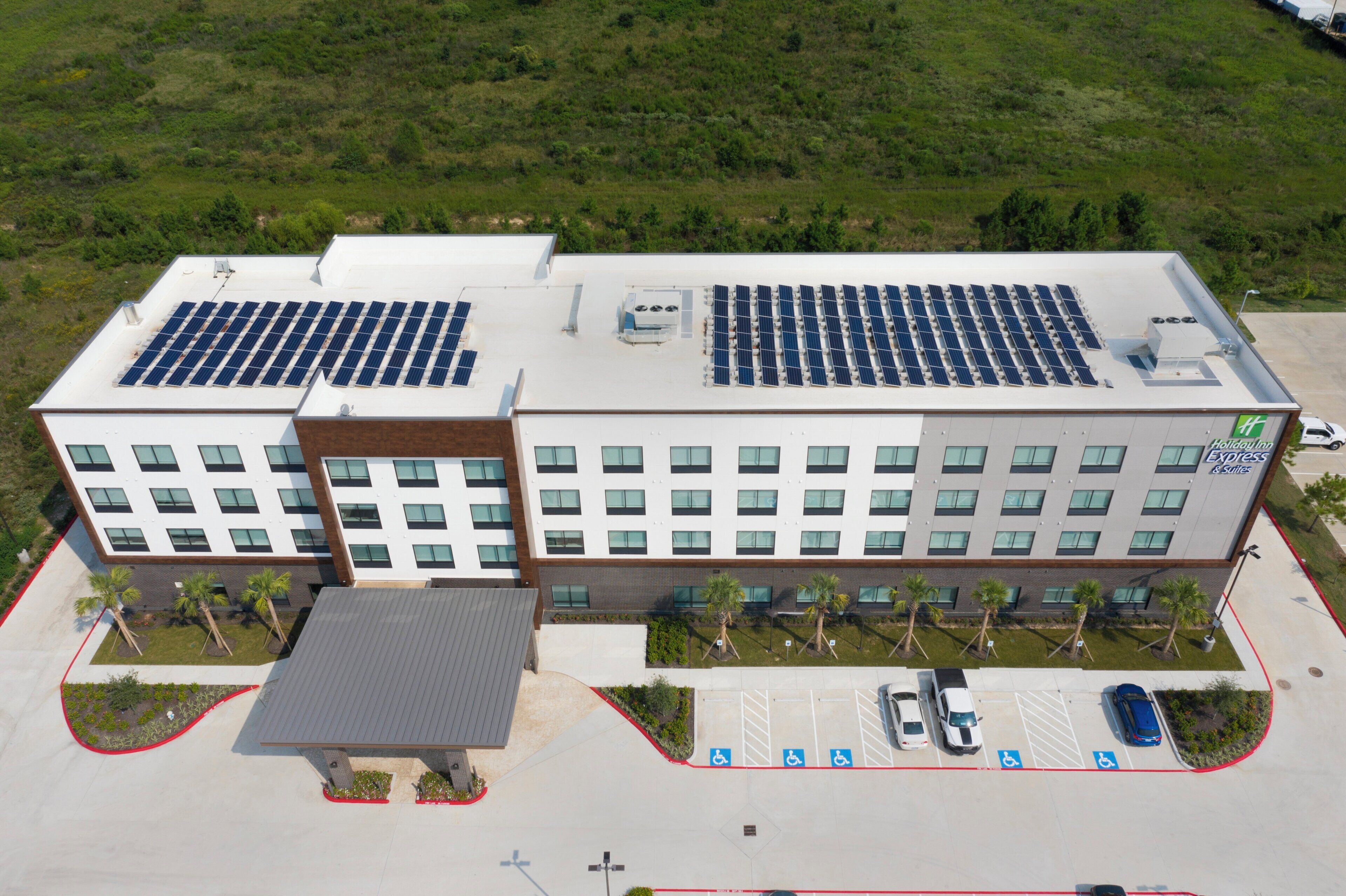 A modern building with solar panels on the roof, a parking lot with handicap-accessible spaces, and a Holiday Inn Express sign.