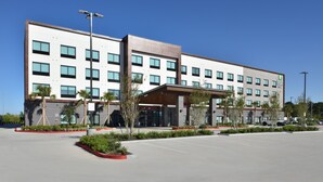A modern hotel with a flat roof, multiple windows, and a covered entrance.