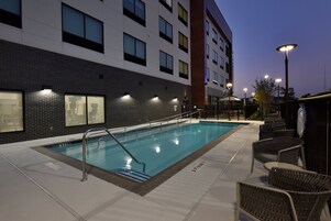 Una piscina al aire libre, sillones reclinables de piscina