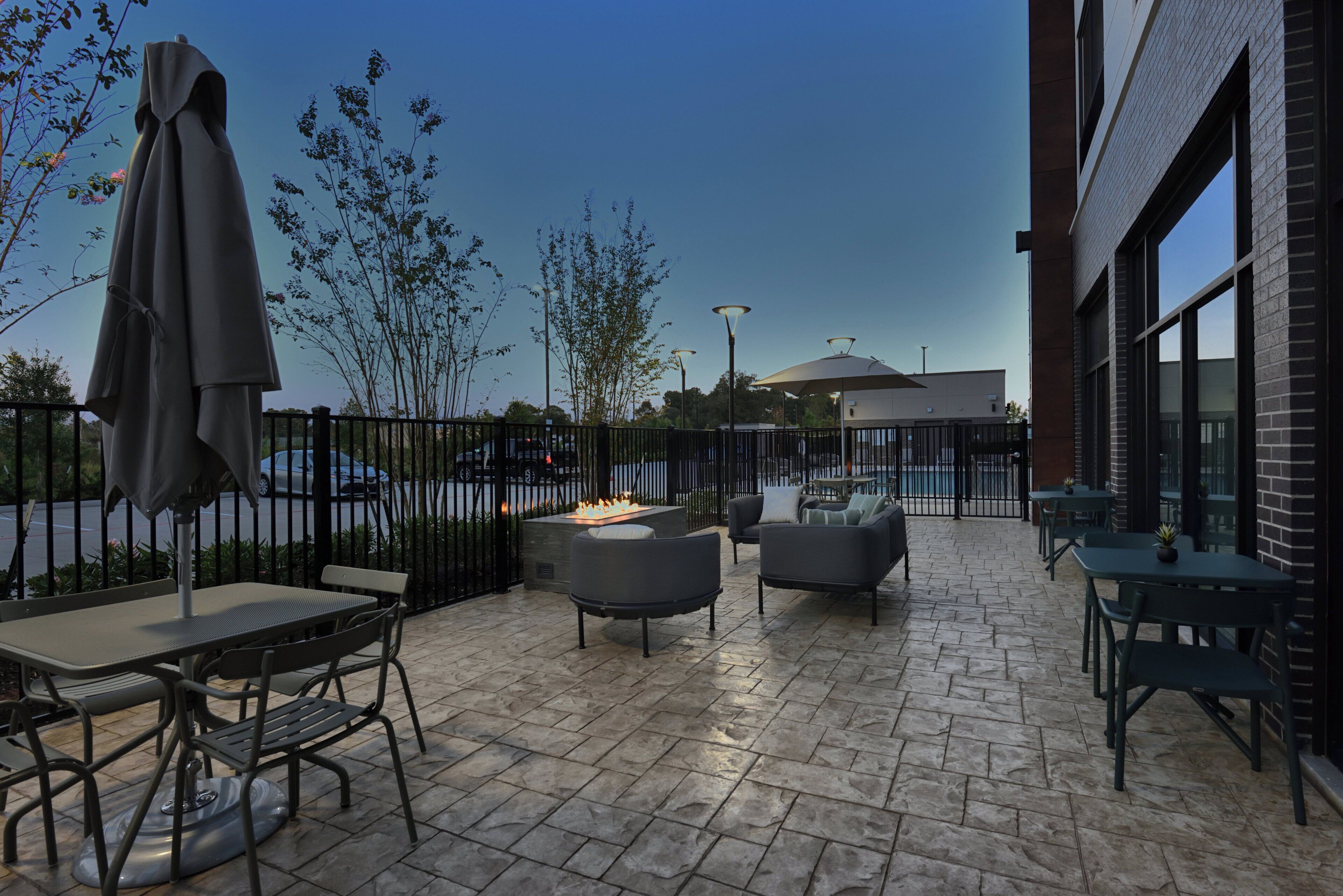An outdoor patio area with seating arrangements, a fire feature, and a view of the street.