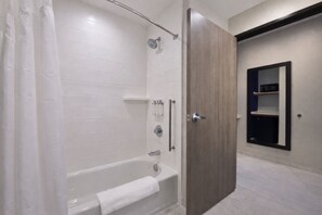 A modern bathroom with a bathtub, shower, and a wooden door. - Holiday Inn Express & Suites Spring - Woodlands Area by IHG (Spring)