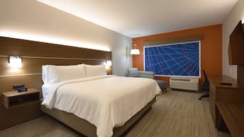 A hotel room with a large bed, bedside tables, a desk, and a TV.